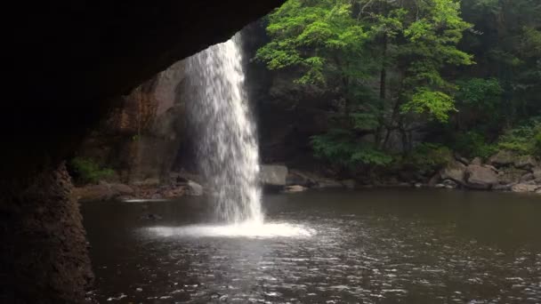 View form Cave under the Picturesque Waterfall in Jungles at Evening Time. Water is Falls in Pool through Sun Beams at Khao Yai National Park, Thailand. — Stock Video