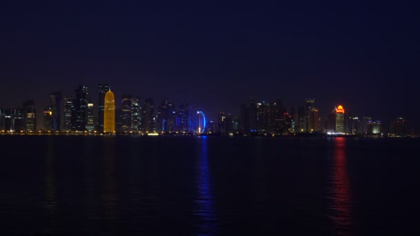 Doha City Night odbicia w wodzie morskiej w Zatoce Perskiej, wideo czasu rzeczywistego, Katar, Bliskim Wschodzie. Oświetlone wieżowce na West Bay odbite w wodzie zatoki. Widok z parku Mia — Wideo stockowe