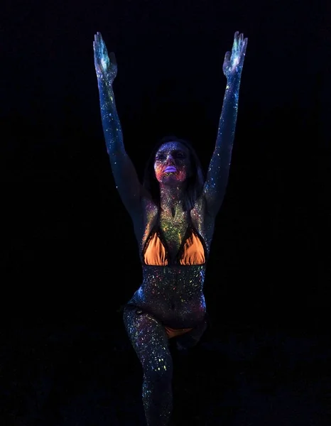 Porträtt av vackra mode kvinna gör Yoga i Uf neonljus. Modell flicka med fluorescerande kreativa psykedeliska Makeup, Art Design av kvinnliga Disco Dancer modell i Uv — Stockfoto