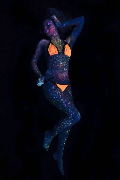 Porträtt av vackra mode kvinna flyger i Uf neonljus. Modell flicka med fluorescerande kreativa psykedeliska Makeup, Art Design av kvinnliga Disco Dancer modell i Uv — Stockfoto