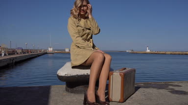 Çekici genç sarışın kadın Vintage çanta siperde yaklaşım Jacht iskelede oturuyor