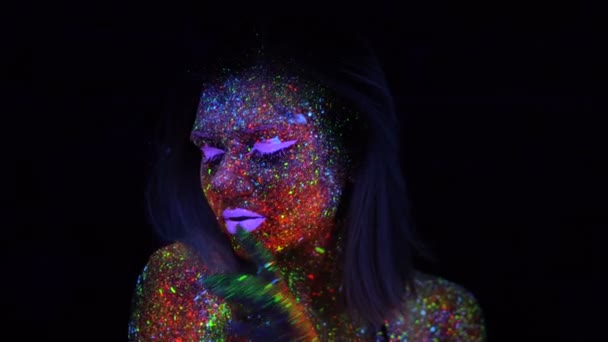 Retrato de bela mulher de moda em luz UV de néon. Menina modelo com maquiagem psicodélica criativa fluorescente, design de arte do modelo de dançarina de disco feminino em UV — Vídeo de Stock