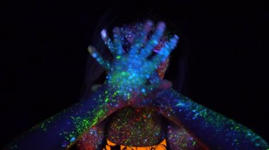 Mor saç Neon Uv ışığında dans ile güzel bir kadın portresi. Model kız floresan yaratıcı Psychedelic makyaj, elini yüzünü önünde Defocused hamle ile.