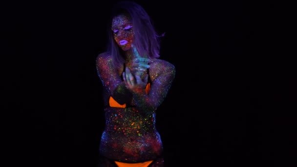 Portretul unei femei frumoase cu păr purpuriu care dansează în lumina UV neon. Fata model cu machiaj psihedelic creativ fluorescent, design artistic al modelului de dansator Disco feminin în UV — Videoclip de stoc
