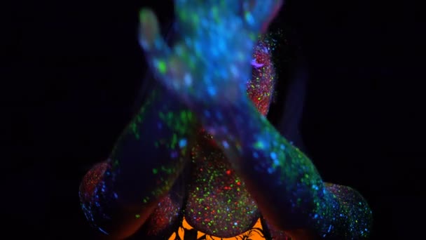 Ritratto di Bella Donna con Capelli Viola Danza in Luce UV al Neon. Modello ragazza con fluorescente creativo psichedelico makeup, si muove la mano di fronte al viso sfocato . — Video Stock