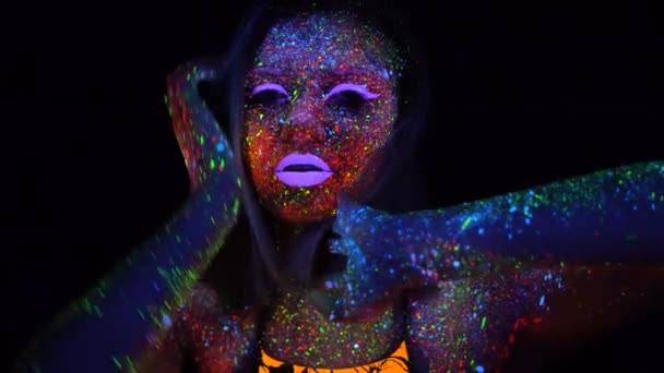 Portrait de belle femme aux cheveux violets dansant au néon UV. Modèle fille avec fluorescent créatif psychédélique maquillage, Déplace sa main devant le visage déconcentré . — Video