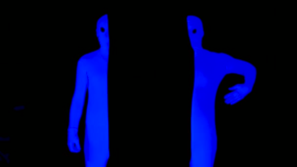 UV-Strahlung halbiert die pantomimische Interaktion. Die eine Hälfte legt Hand in Hand in eine andere, kontrastreiche Komödie. Blau auf schwarz Szene im Schwarzlicht. — Stockvideo