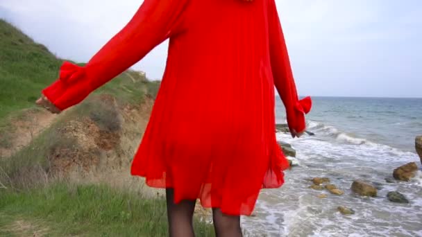 Glad ung kvinna i röd klänning cirklande och ha roligt på havet kusten klippan — Stockvideo