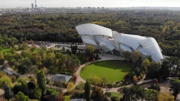 Survol du bâtiment moderne du musée de la Fondation Louis Vuitton à Paris, France. Tour Eiffel en arrière-plan, forêt de Boulogne autour . — Video