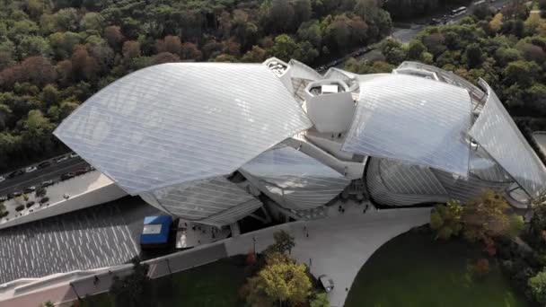 Flying over Louis Vuitton Foundation museum modern building in Paris, France (en inglés). Torre Eiffel en el fondo, bosque de Boulogne alrededor . — Vídeo de stock