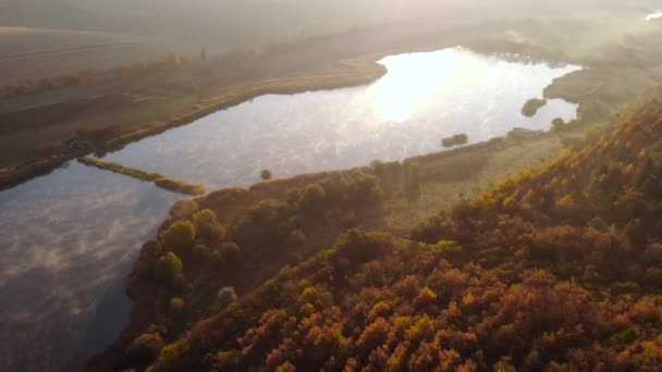 Létání nad jezerem s mlhou nad vodou. Ranní mlha, mlha nad jezerem. Letecká mlha na podzim. Podzimní barvy Evropy. Studený ranní jezírko. Mlha nad jezerem na venkově — Stock video