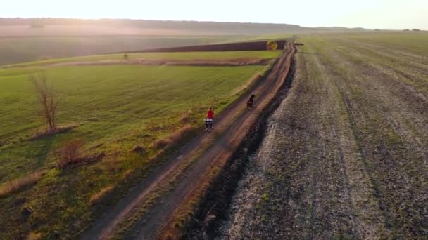 AEREO Volare sopra ragazzi in bicicletta su strada sterrata passando campi in campagna. Ora d'oro . — Video Stock