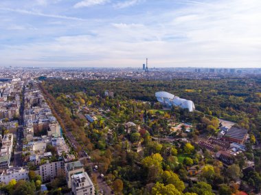 FRANCE, PARIS - OCT 2019: Aerial shot of Louis Vuitton Foundation museum modern building in Paris, France. Eiffel Tower on background, Boulogne forest around. clipart