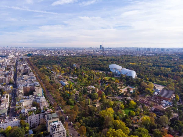 FRANCE, PARIS - OCT 2019: Aerial shot of Louis Vuitton Foundation museum modern building in Paris, France. Eiffel Tower on background, Boulogne forest around. — Stock Photo, Image