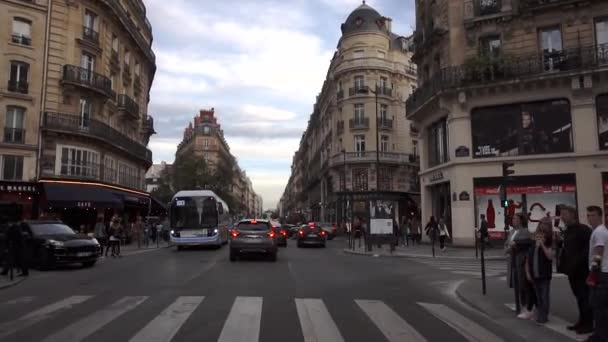 Париж, Франция - октябрь 2018: Проезд по типичной парижской улице. Автомобили едут по дороге, пешеходы идут по тротуару, французские бутики и фасады — стоковое видео