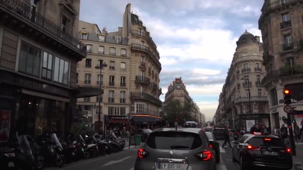 Париж, Франция - октябрь 2018: Проезд по типичной парижской улице. Автомобили едут по дороге, пешеходы идут по тротуару, французские бутики и фасады — стоковое видео