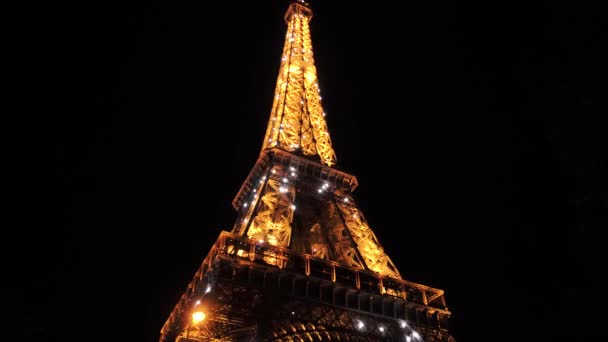 Parpadeo intermitente de la torre Eiffel en París por la noche. Caliente brillante construcción de metal enorme — Vídeo de stock