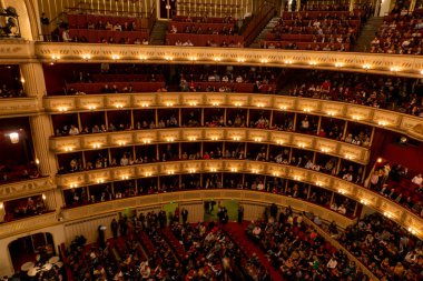 Viyana, Avusturya - Ekim 2019: Ziyaretçilerle birlikte Viyana Devlet Opera Salonu Performans Salonu. Wiener Staatsoper merdivenleri, yuvarlak virajlı koltuklar seyirciler.
