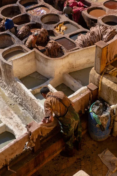 Μαρόκο, Φεξ - Ιανουάριος 2019: Άντρας που εργάζεται στο βυρσοδεψείο Chouara στην παλιά Μεντίνα της Φεζ, ένα παραδοσιακό και παλιό βυρσοδεψείο με εργάτες που εργάζονται με μεθόδους κατασκευής δέρματος — Φωτογραφία Αρχείου