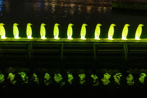 Σύγχρονη Λαμπερή κατασκευή τέχνης στην Πράγα. Χρώμα λεμονιού ακατέργαστο πιγκουίνων που αντανακλάται στο νερό τη νύχτα — Φωτογραφία Αρχείου