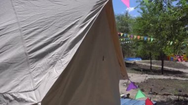 Siyah bikinili genç seksi kadın yazın glamping bölgesinde büyük beyaz çadırdan çıkıyor.