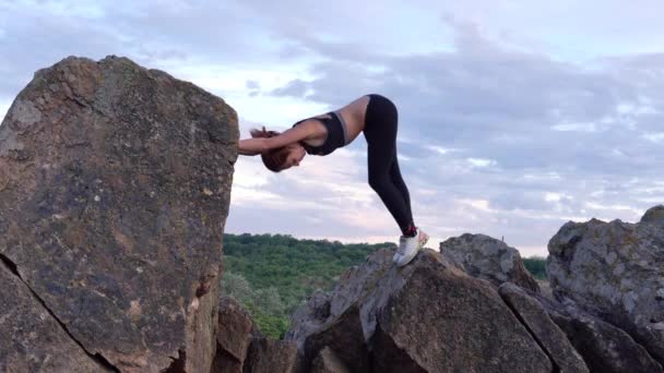 Sporty woman practicing yoga and gymnastics exercises on mountain cliff with beautiful landscape ob background. Healthy lifestyle. active extreme. — Stock Video