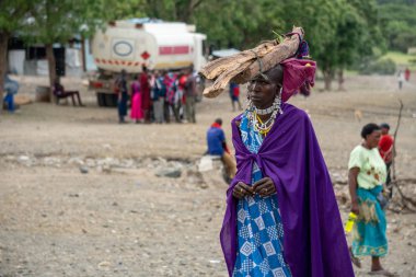 TANZANIA, MASAI VILLAGE - JANUARY 2020: woman with logs on the head in native masai village Engare Sero on the coast of Natron Lake in Maasailand, Arusha district