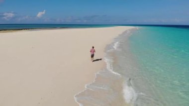 Zanzibar. Nakupenda Adası 'nın kar beyazı kumsalında koşan sportif bir adam. Bir günde sadece birkaç saat ortaya çıkıyor. Hava aracı görüntüsü