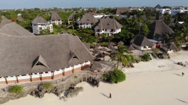 Tanzanya 'nın Zanzibar adasındaki Nungwi' de güzel beyaz kumlu okyanus kıyısındaki lüks okyanus manzaralı plaj şemsiyelerinin hava manzarası.
