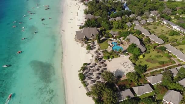 Вид с воздуха на соломенную крышу пляжных зонтиков роскошного курорта с видом на океан на красивом белом песке побережья океана в Нунгви на острове Занзибар, Танзания — стоковое видео