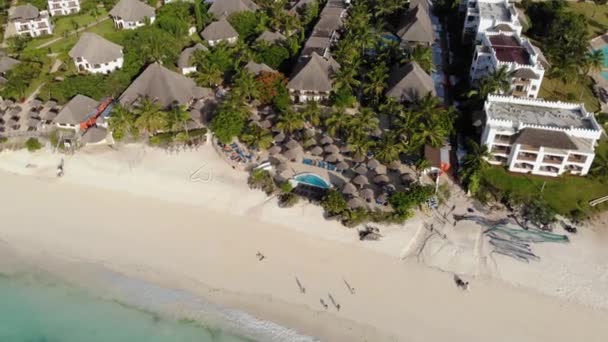 Luftaufnahme des Strohdachs von Sonnenschirmen des luxuriösen Ocean View Resorts an der wunderschönen weißen Sandmeerküste in Nungwi auf der Insel Sansibar, Tansania — Stockvideo