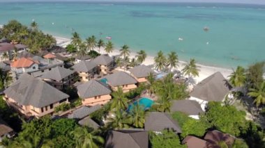 Tanzanya 'nın Zanzibar adasındaki Nungwi' de güzel beyaz kumlu okyanus kıyısındaki lüks okyanus manzaralı plaj şemsiyelerinin hava manzarası.
