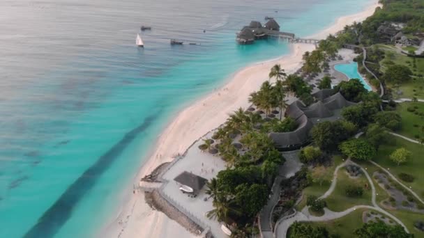Belle maison de chaume sur pilotis à Zanzibar Plage de Nungwi en soirée avec vue aérienne bleue sur l'océan Indien — Video