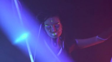 Neon UF Light 'ta Dreadlock' lu bir kızın portresi. Psikedelik Makyajlı Parlak tüplerle dans eden manken kız, UV 'deki Kadın Disko Dansçısı Modeli, Renkli Soyut Makyaj.