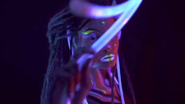 Portretul unei fete cu Dreadlocks în Neon UF Light. Model Girl dansând cu tuburi strălucitoare cu machiaj psihedelic, Design artistic al modelului de dansator Disco feminin în UV, machiaj abstract colorat . — Videoclip de stoc