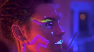 Neon UF Light 'ta Dreadlock' lu bir kız uydurmak. Flüoresan Yaratıcı Psikedelik Makyajlı Model Kız, UV 'deki Kadın Disko Dansçısı Modeli, Renkli Soyut Makyaj. Dans eden bayan.