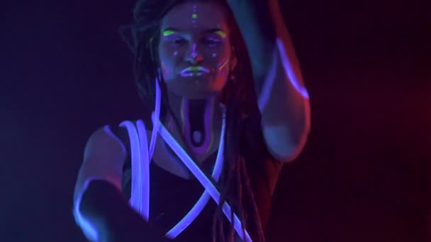 Porträt eines Mädchens mit Dreadlocks in Neon UF Light. Model Girl tanzt mit glühenden Röhren mit Psychedelic MakeUp, Art Design der weiblichen Disco-Tänzerin Model in UV, Buntes abstraktes Make-up. — Stockvideo