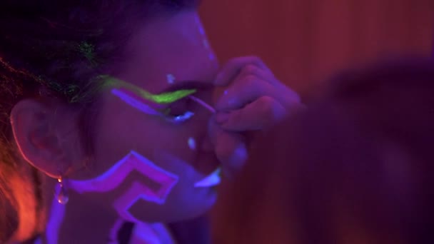 Een meisje maken met dreadlocks in Neon UF Light. Model Girl with Fluorescent Creative Psychedelic MakeUp, Art Design of Female Disco Dancer Model in UV, Kleurrijke Abstract Make-up. Dansende Dame — Stockvideo