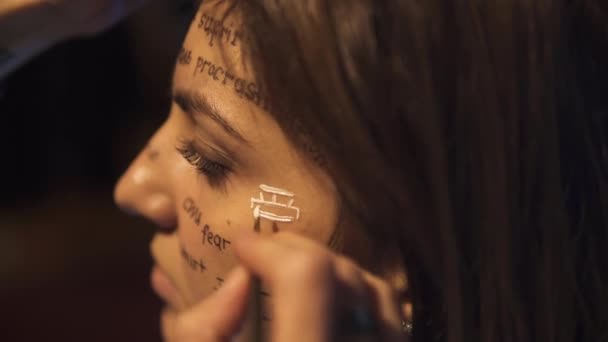 Dipingere il viso delle ragazze. Parole su diverse lingue sono scritte sul volto della ragazza carina — Video Stock