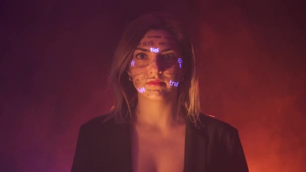 Chica en la niebla y Dramática luz cálida con palabras escritas en diferentes idiomas en su cara. Hermoso modelo con maquillaje creativo de neón fluorescente UV. cara de cerca — Vídeo de stock