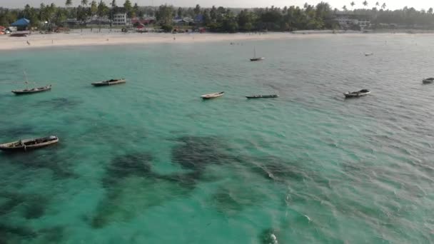 Aerial Drone girato su barche tradizionali Unguja Dhow vicino alla bellissima linea costiera tropicale a Zanzibar. Spiaggia di Nungwi in un giorno con blu Oceano Indiano — Video Stock