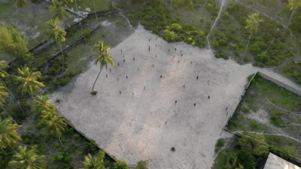 Voler au-dessus des gars qui jouent au football sur le terrain de football dans le village tanzanien de Paje à East Zanzibar île vue aérienne. Tanzanie, Afrique — Video