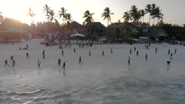 Flyger ovanför killarna spelar fotboll på stranden strandlinjen vid solnedgången tid i Tanzanian Paje byn på östra Zanzibar ön antenn utsikt. Tanzania, Afrika — Stockvideo