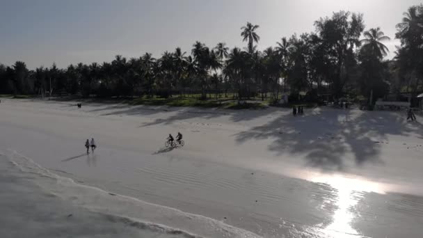 Pessoas caminhando pela praia tropical Paraíso Paje na ilha de East Zanzibar. Hora do pôr do sol vista aérea. Tanzânia, África — Vídeo de Stock