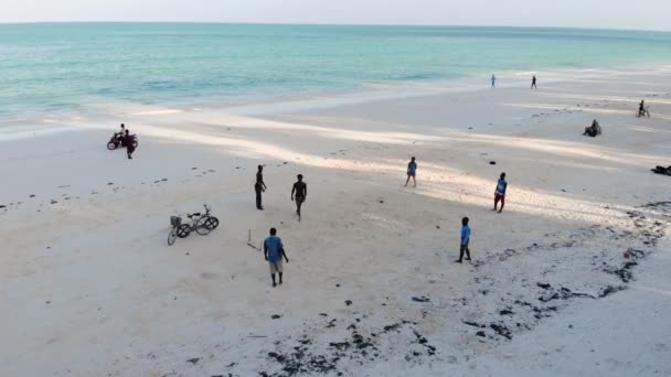 Voler au-dessus des gars jouant au football sur la ligne de plage de bord de mer à l'heure du coucher du soleil dans le village tanzanien de Paje à East Zanzibar île vue aérienne. Tanzanie, Afrique — Video