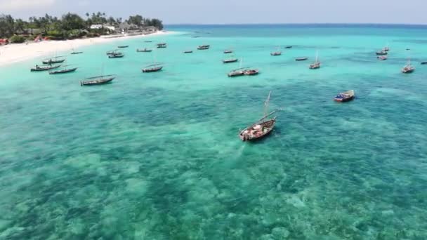 Légi drón lövés a hagyományos Unguja Dhow hajók közelében a gyönyörű trópusi partvonal Zanzibar. Nungwi strand egy nap alatt kék türkiz Indiai óceán — Stock videók