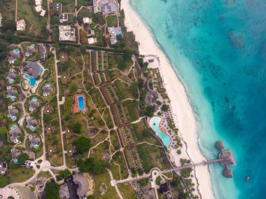 Hint okyanusunun Turkuaz Suyu 'nda akşam saatlerinde Zanzibar Kendwa plajındaki Güzel Thatch stilt ev restoranı ve tatil köyü üzerine Top View