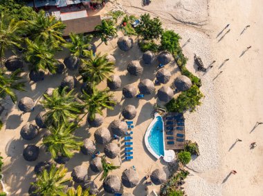 Tanzanya 'nın Zanzibar adasındaki Nungwi' de güzel beyaz kumlu okyanus kıyısındaki lüks okyanus manzaralı Thatched plaj şemsiyelerinin üst hava manzarası.