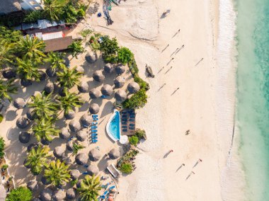Tanzanya 'nın Zanzibar adasındaki Nungwi' de güzel beyaz kumlu okyanus kıyısındaki lüks okyanus manzaralı Thatched plaj şemsiyelerinin üst hava manzarası.