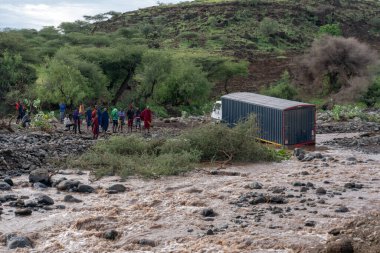 TANZANIA, ARUSHA - 2020: Masai halkı kıyıda durup Ağır Kargo Kamyonu nehirde mahsur kalırken ne yapacaklarına karar veriyorlar. Ford Afrika Anakara Yolları 'nda. Doğu Afrika